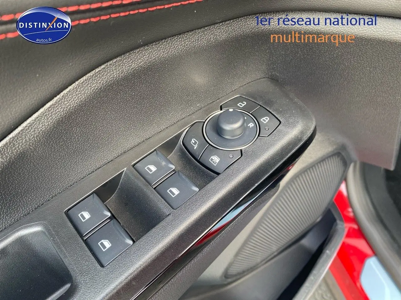 Vue rapprochée des commandes des vitres et rétroviseurs sur la porte avant gauche d’un Ford Puma rouge métallisé.