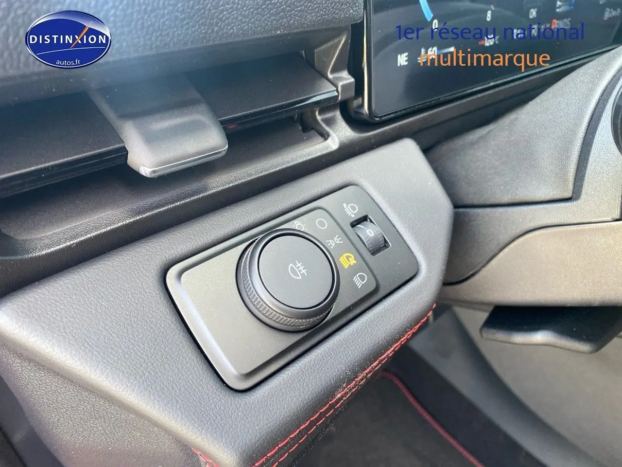 Détail du bouton de réglage des phares sur la gauche du tableau de bord du Ford Puma rouge.