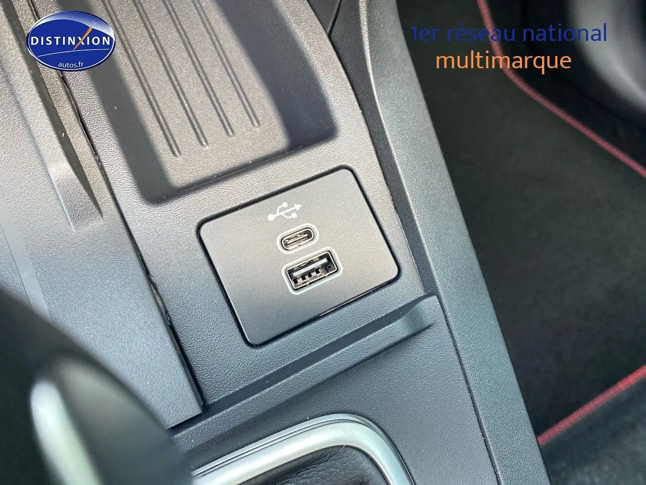 Gros plan sur les ports USB-C et USB-A dans la console centrale du Ford Puma, avec surpiqûres rouges visibles.