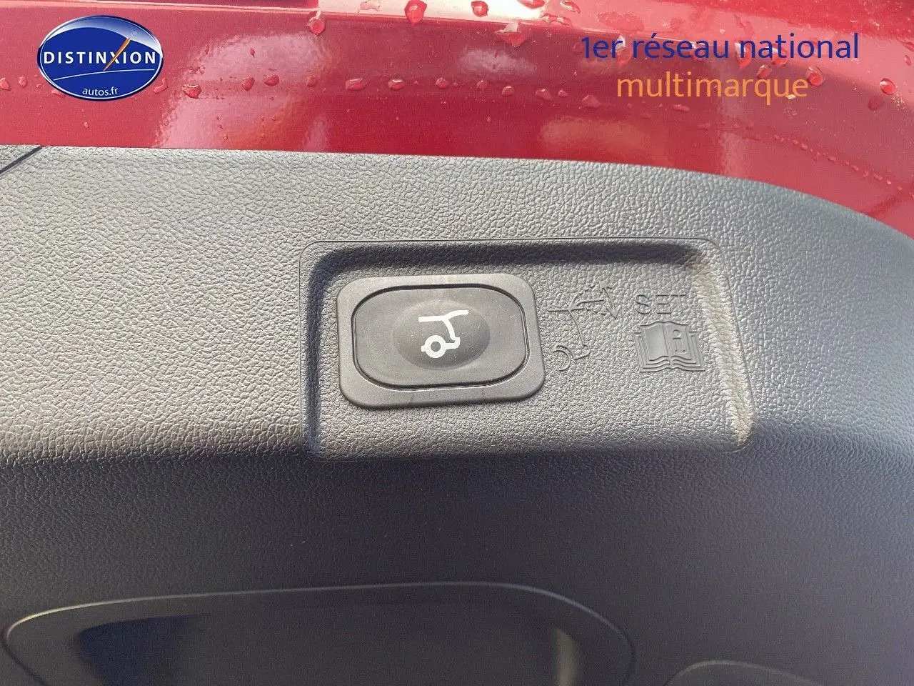Gros plan sur le bouton d'ouverture électrique du coffre sur la partie intérieure rouge métallisée du Ford Puma 2026.