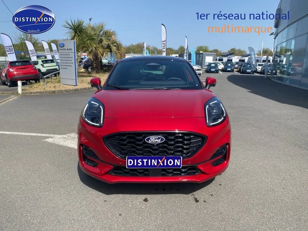 Vue frontale d'une Ford Puma rouge métallisée avec calandre noire et phares LED marqués, sur parking extérieur.