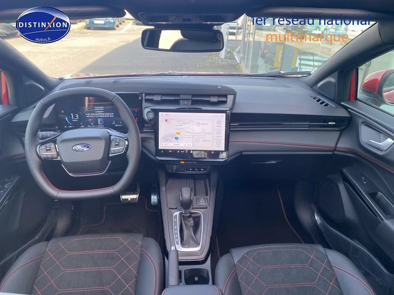 Vue intérieure avant du Ford Puma rouge avec volant multifonction, écran tactile central et surpiqûres rouges sur les sièges sport.