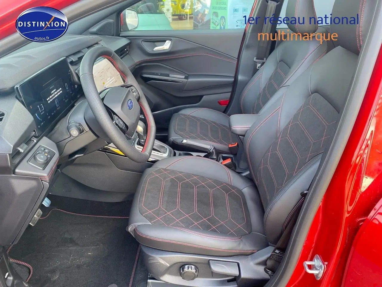 Vue intérieure côté conducteur du Ford Puma rouge, mettant en valeur les sièges sport avec surpiqûres rouges et le volant multifonction.