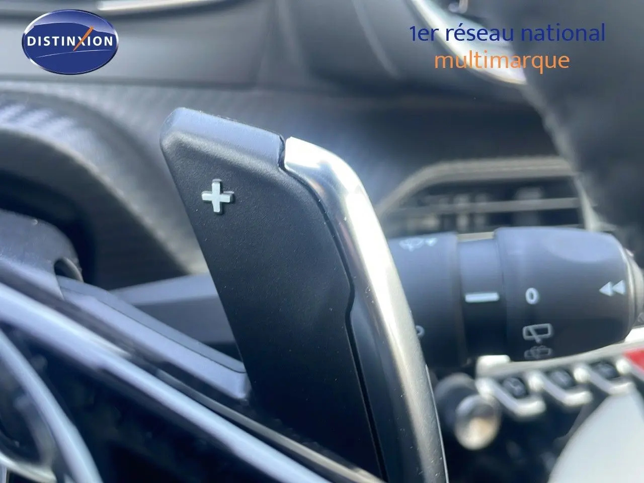 Gros plan sur la palette de changement de vitesse + au volant d’un Peugeot 2008 gris Artense 2025 hybride.