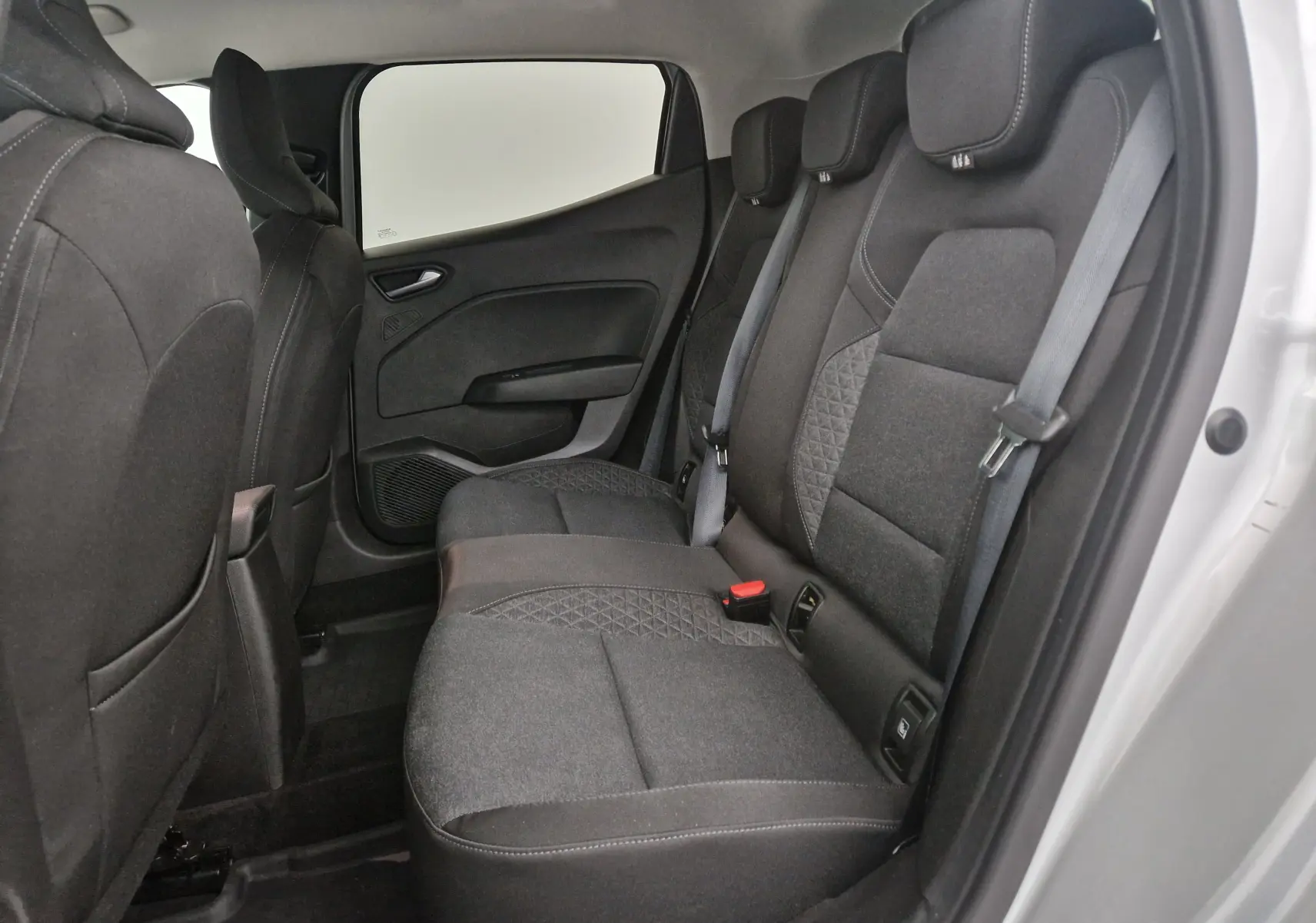 Vue intérieure montrant la banquette arrière en tissu gris foncé de la Renault Clio V 1.0 TCE 90 Zen, côté droit ouvert.