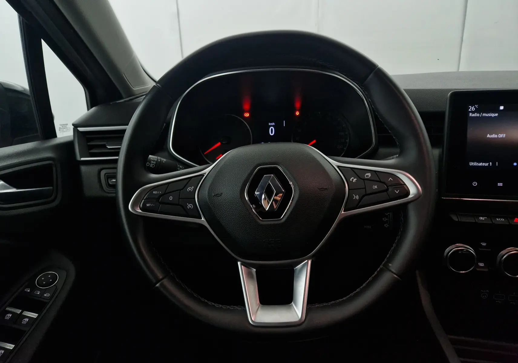 Vue rapprochée du volant noir de la Renault Clio V 1.0 TCE 90 Zen avec tableau de bord et écran tactile allumé.