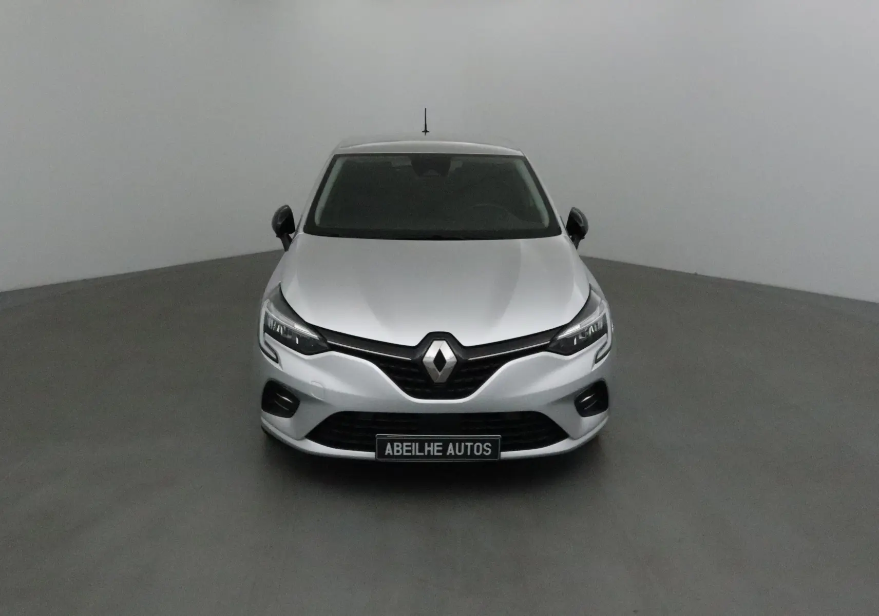 Renault Clio V gris platine vue de face, mettant en valeur la calandre noire et les phares LED modernes.