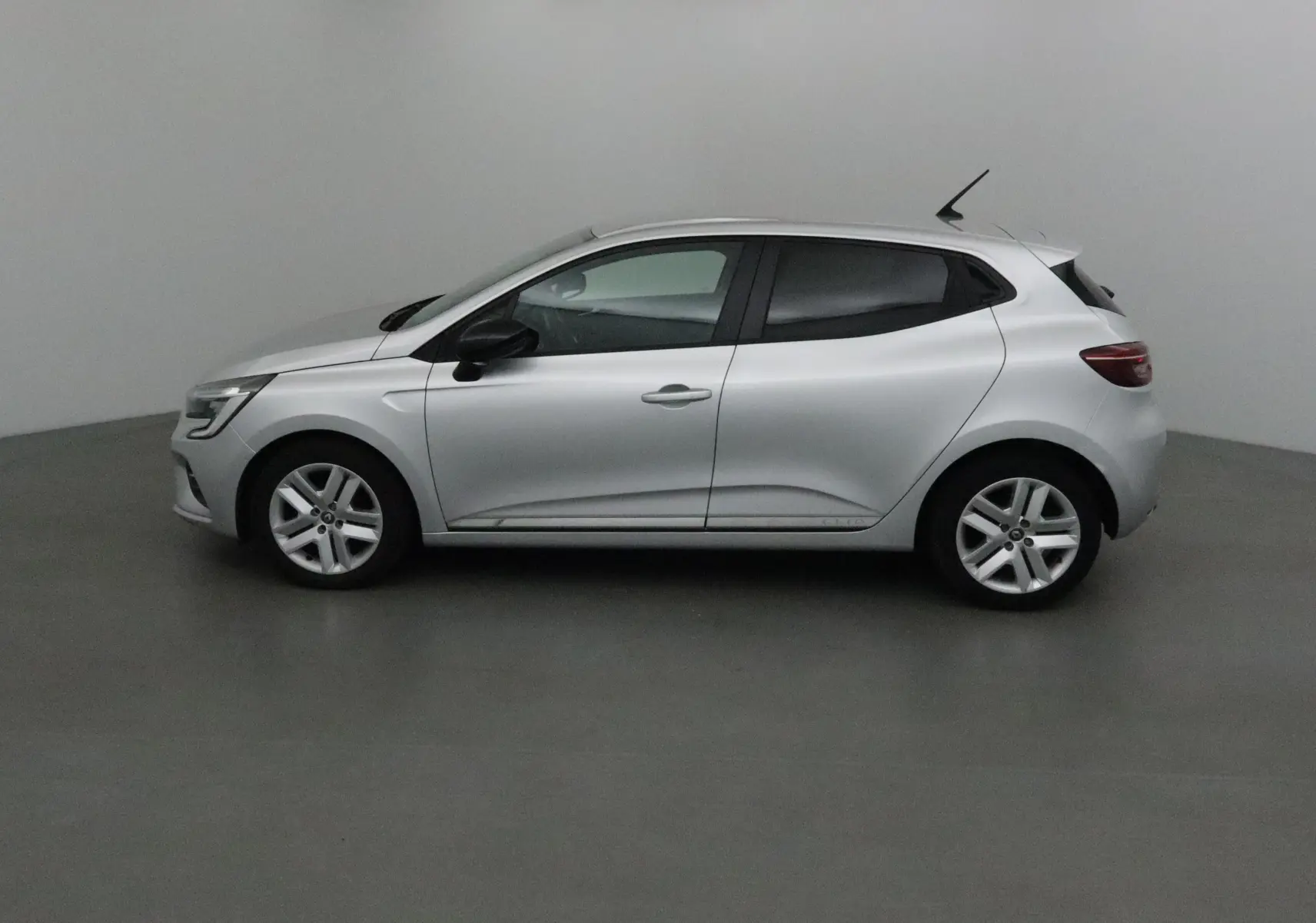 Profil côté gauche d'une Renault Clio V gris platine 2021, compacte et élégante avec des jantes alliage simples.