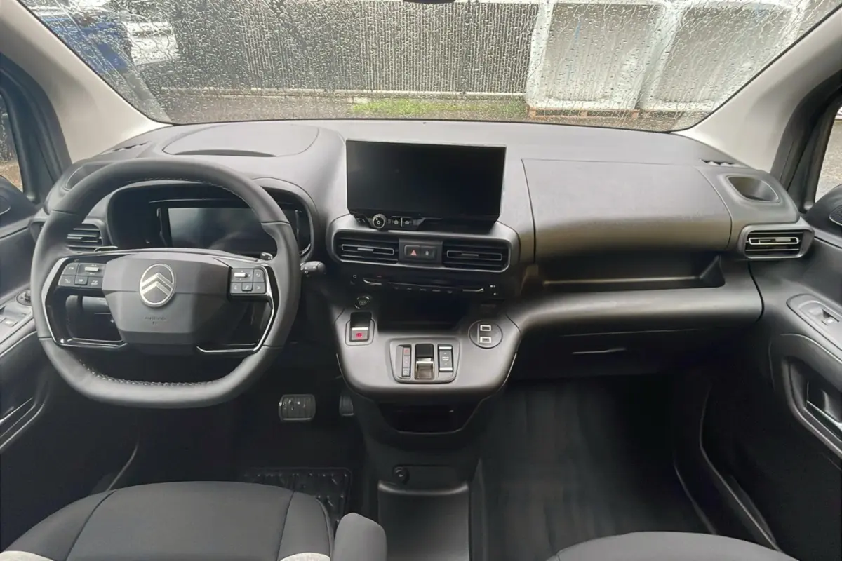 Intérieur du Citroën Berlingo 2025 vue de face, tableau de bord noir avec écran tactile central et volant multifonction.