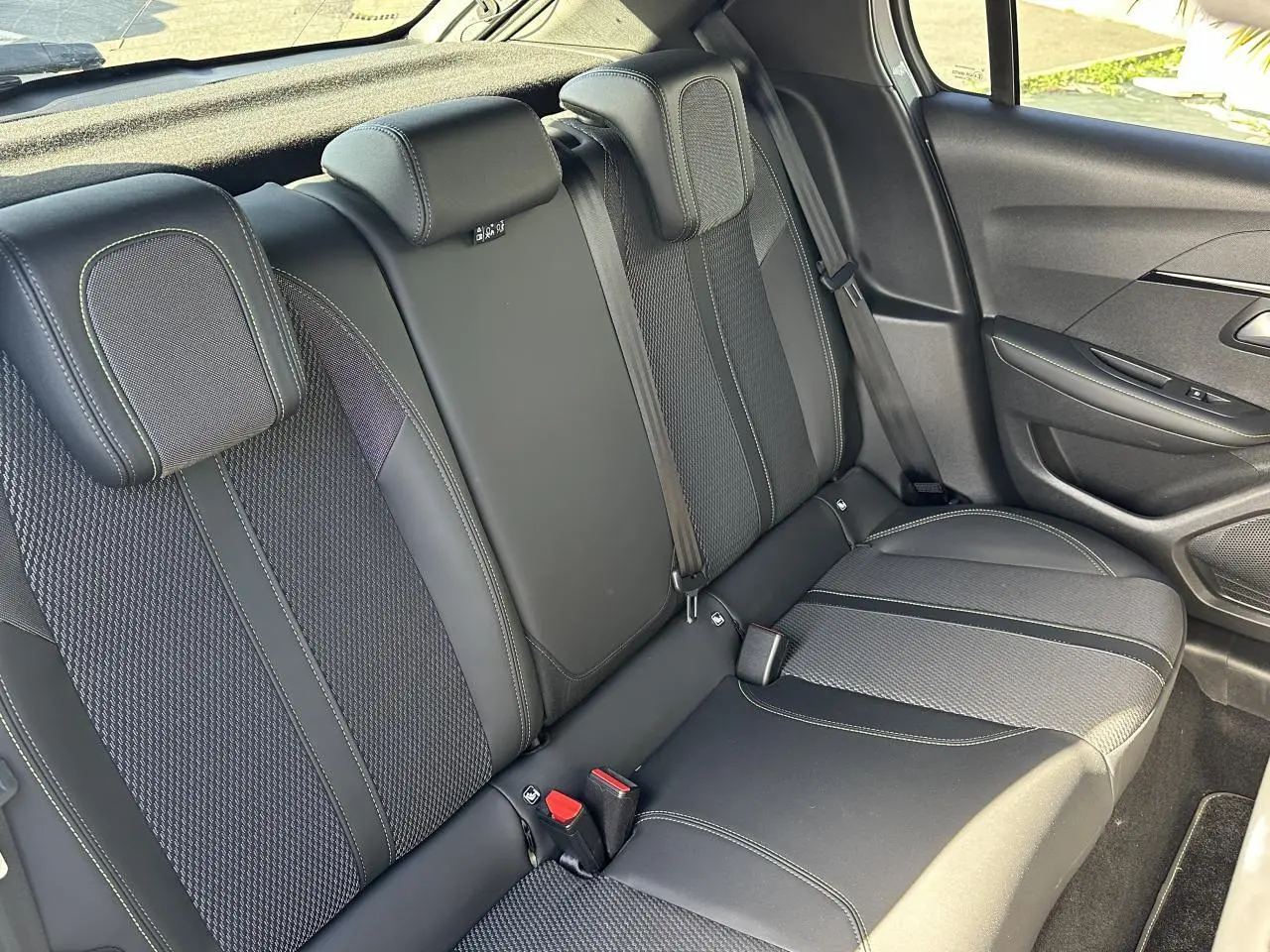 Vue intérieure côté droit des sièges arrière en tissu noir avec surpiqûres vertes de la Peugeot 208 Hybrid 145 e-DSC6 GT 2024
