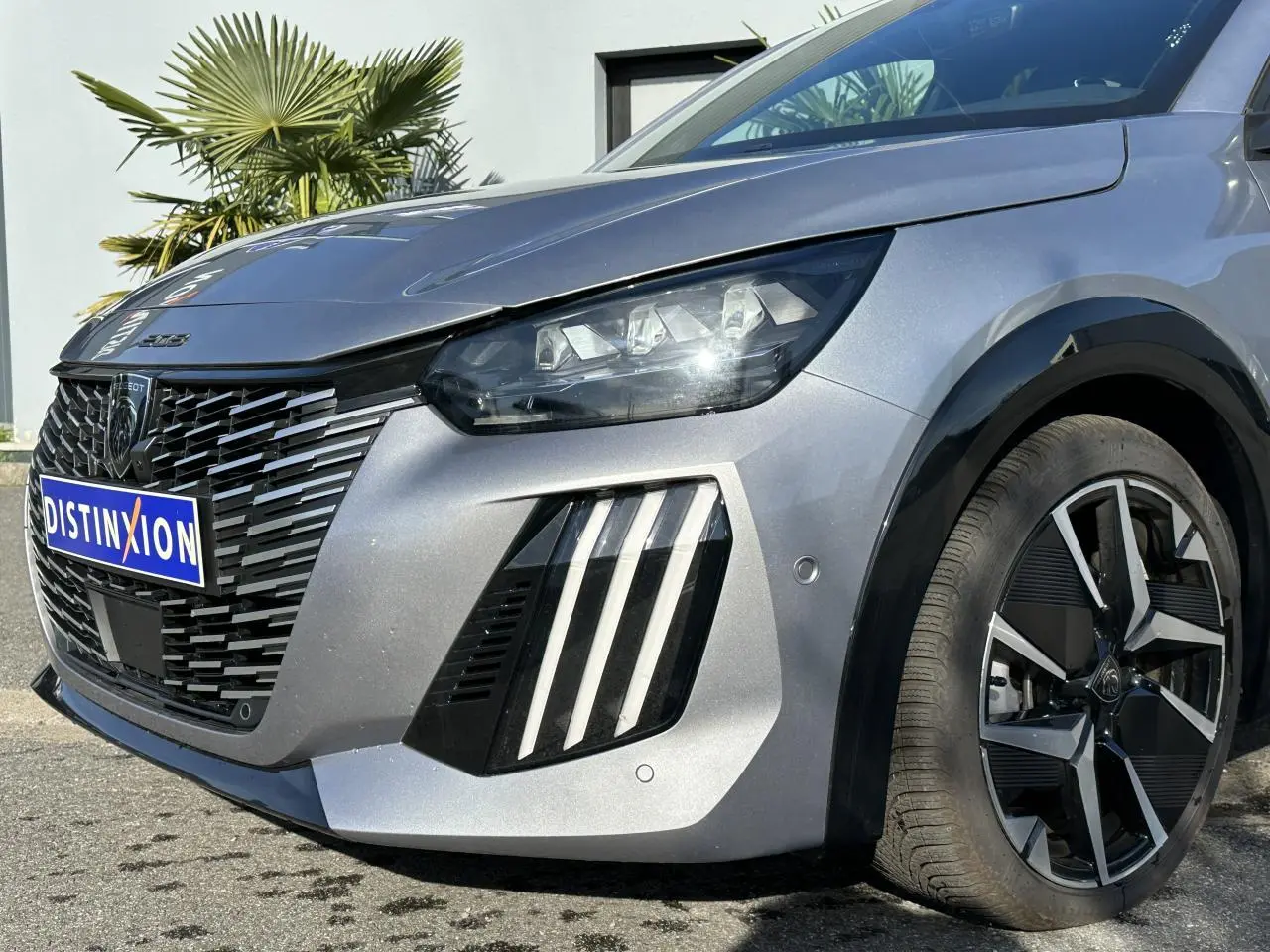 Vue 3/4 avant droit d'une Peugeot 208 Hybrid 145 gris Artense avec calandre noire et jantes alliage diamantées.