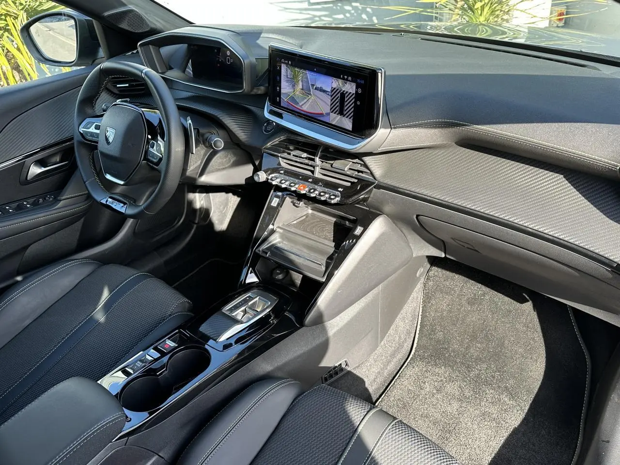 Vue intérieure côté conducteur de la Peugeot 208 Hybrid 145 GT avec écran tactile 10 pouces et sellerie noire.