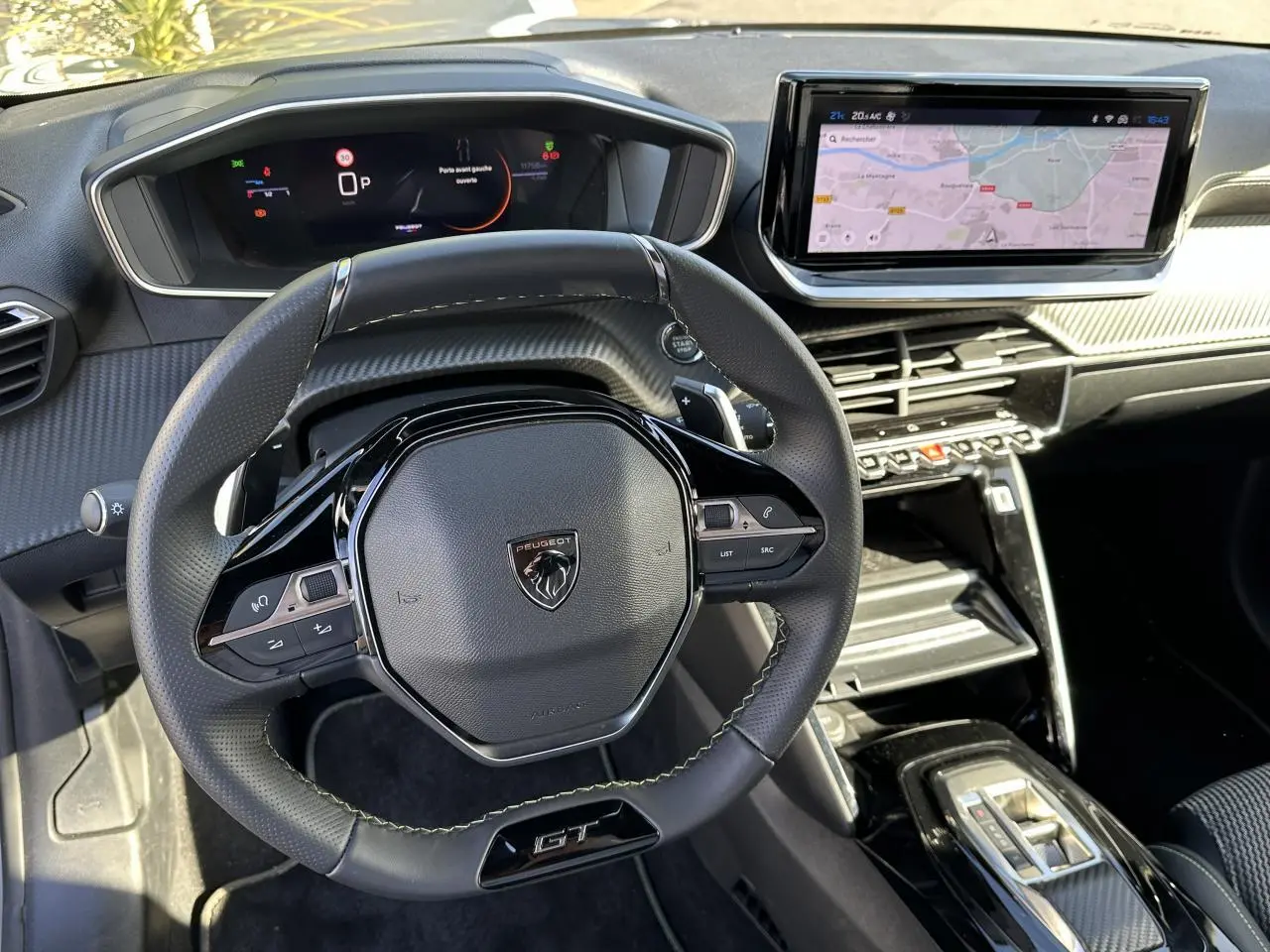 Intérieur du Peugeot 208 Hybrid 145 GT montrant le volant cuir GT et l'écran tactile GPS 10 pouces en vue avant centrale.