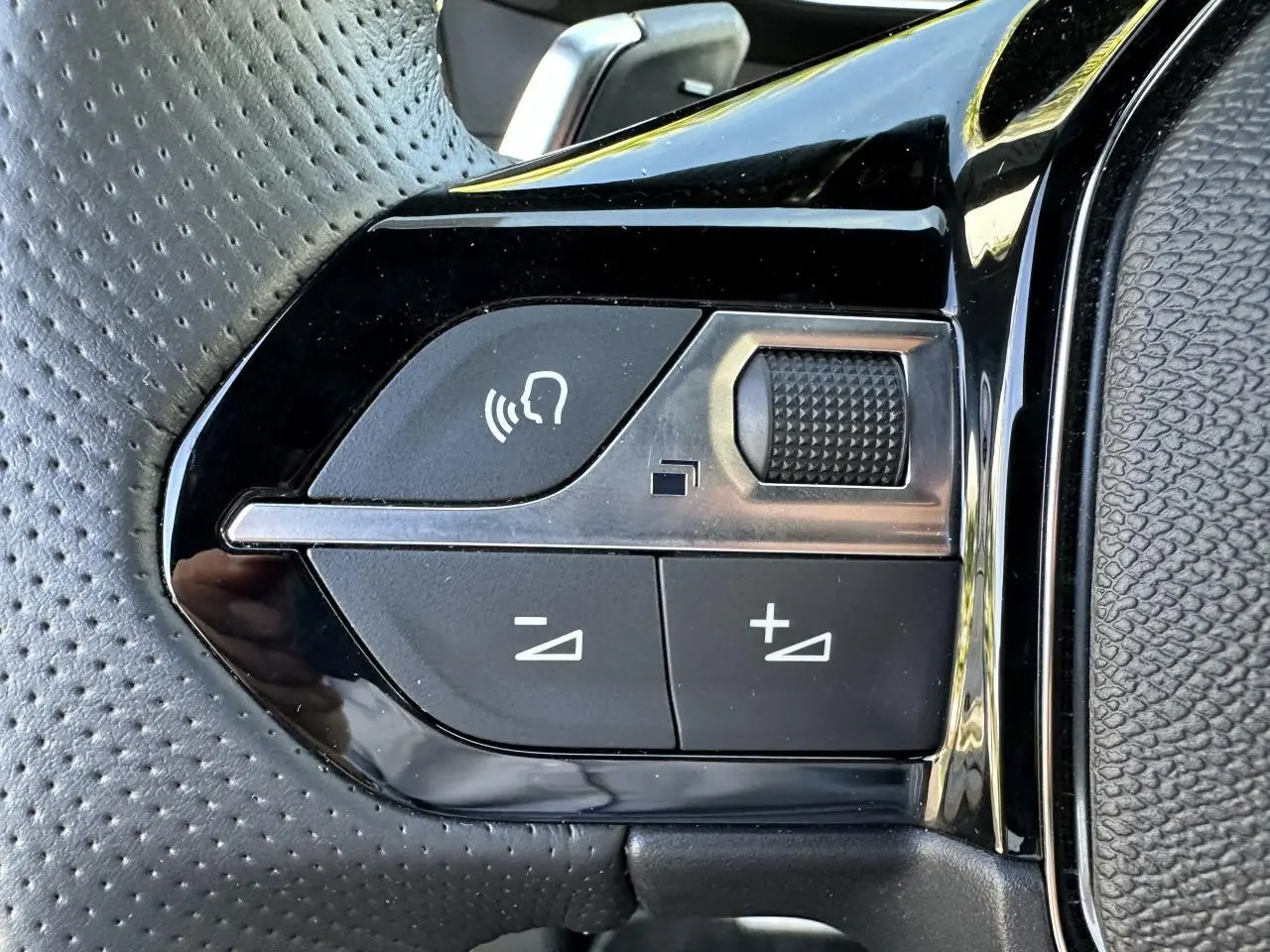 Gros plan sur les commandes vocales et volume du volant cuir perforé du Peugeot 208 Hybrid 145 e-DSC6 GT 2024.