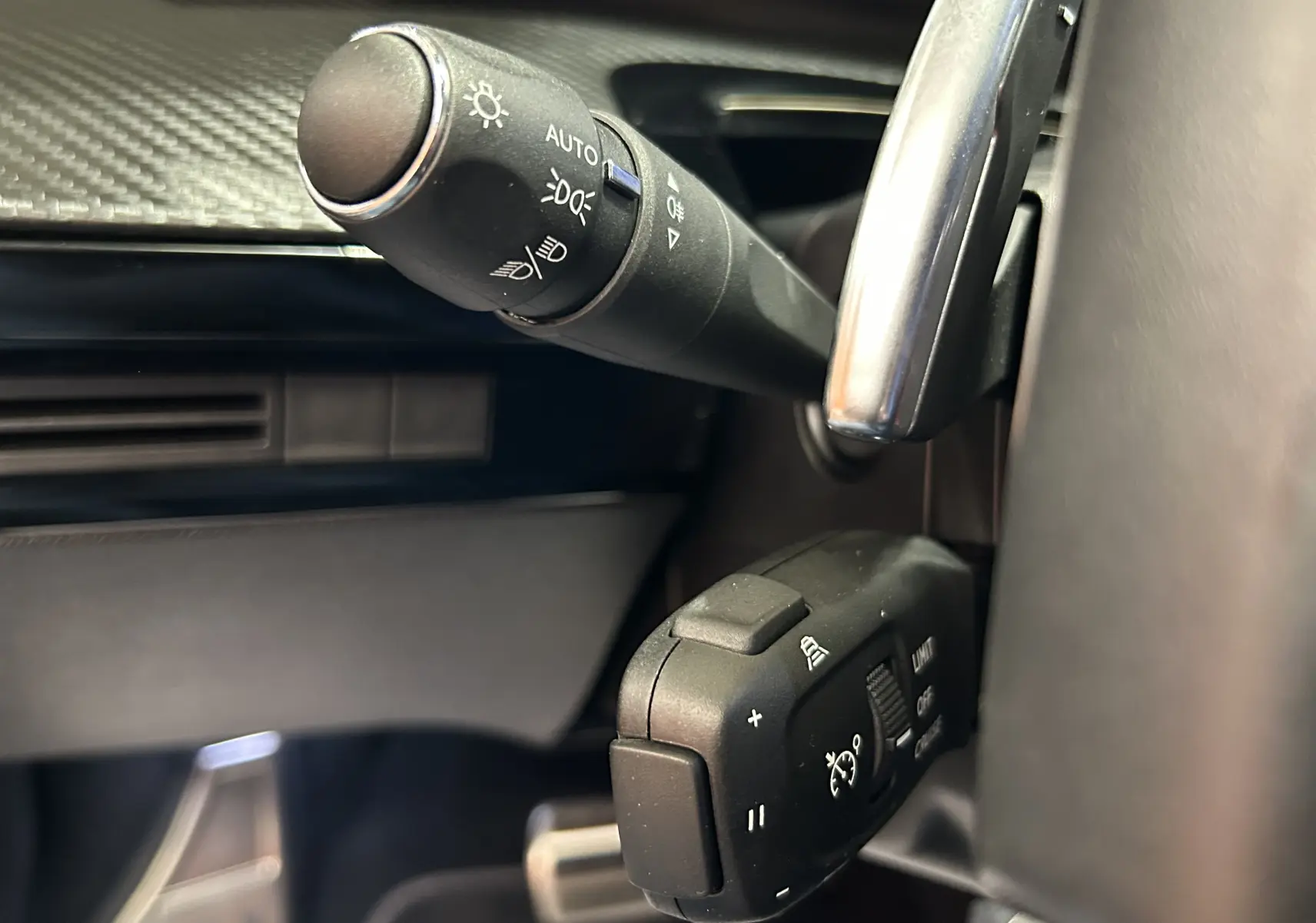 Gros plan sur la commande de régulateur de vitesse et éclairage du Peugeot 508 SW gris artense, côté gauche du volant.