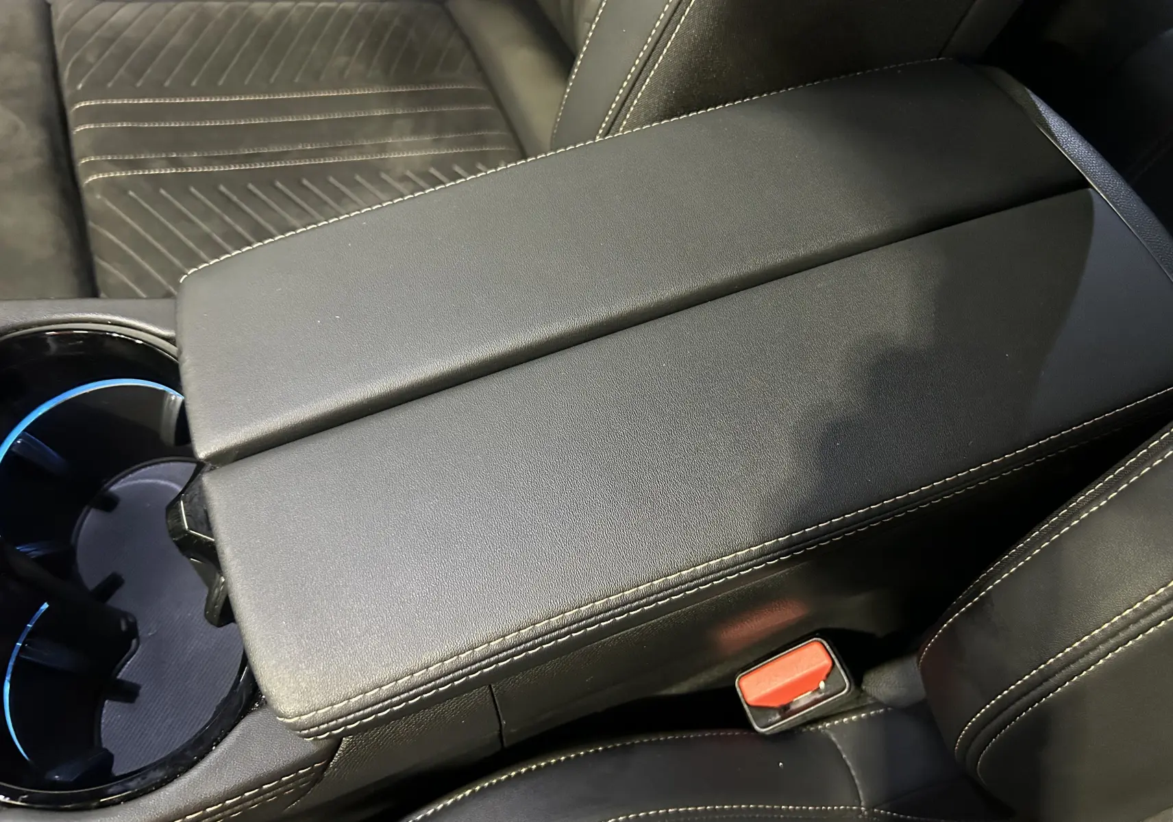 Gros plan sur l'accoudoir central en cuir noir avec surpiqûres blanches de la Peugeot 508 SW GT 2024.