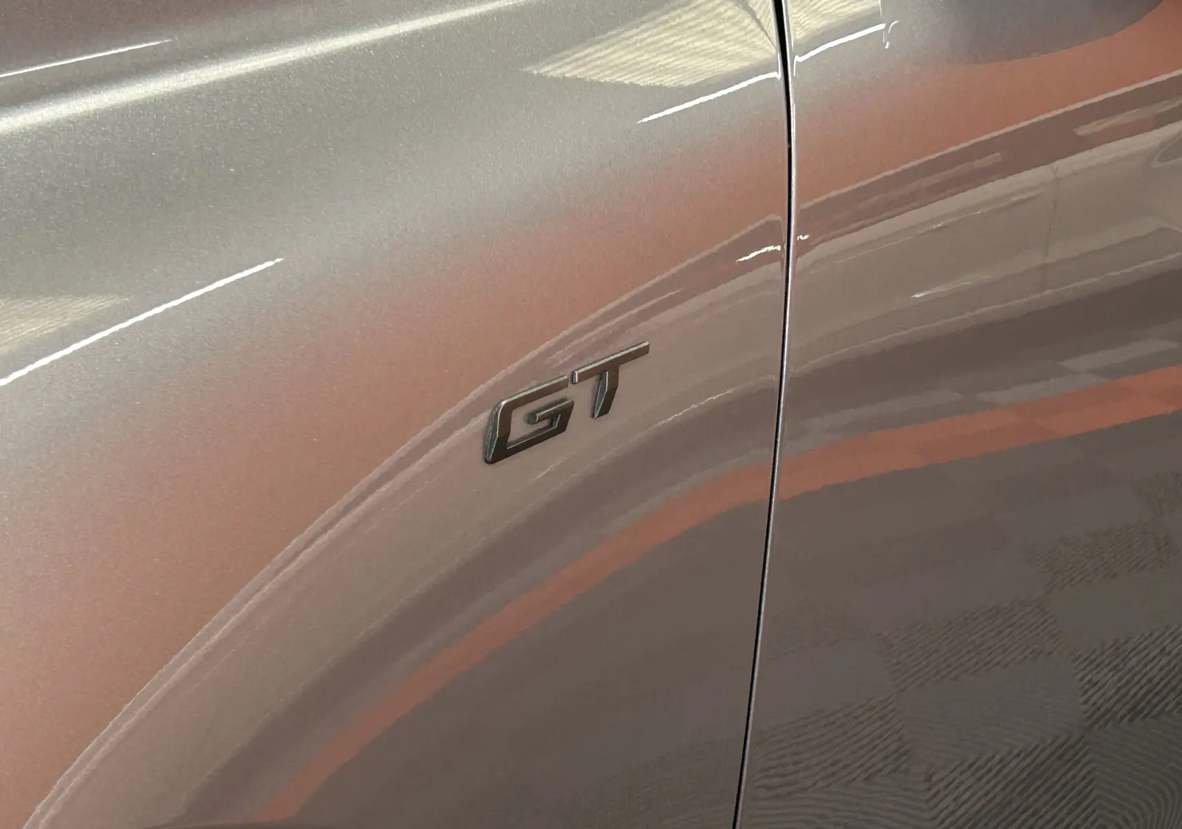 Gros plan sur l'emblème GT noir sur la porte avant côté gauche d'une Peugeot 508 SW gris artense brillante.