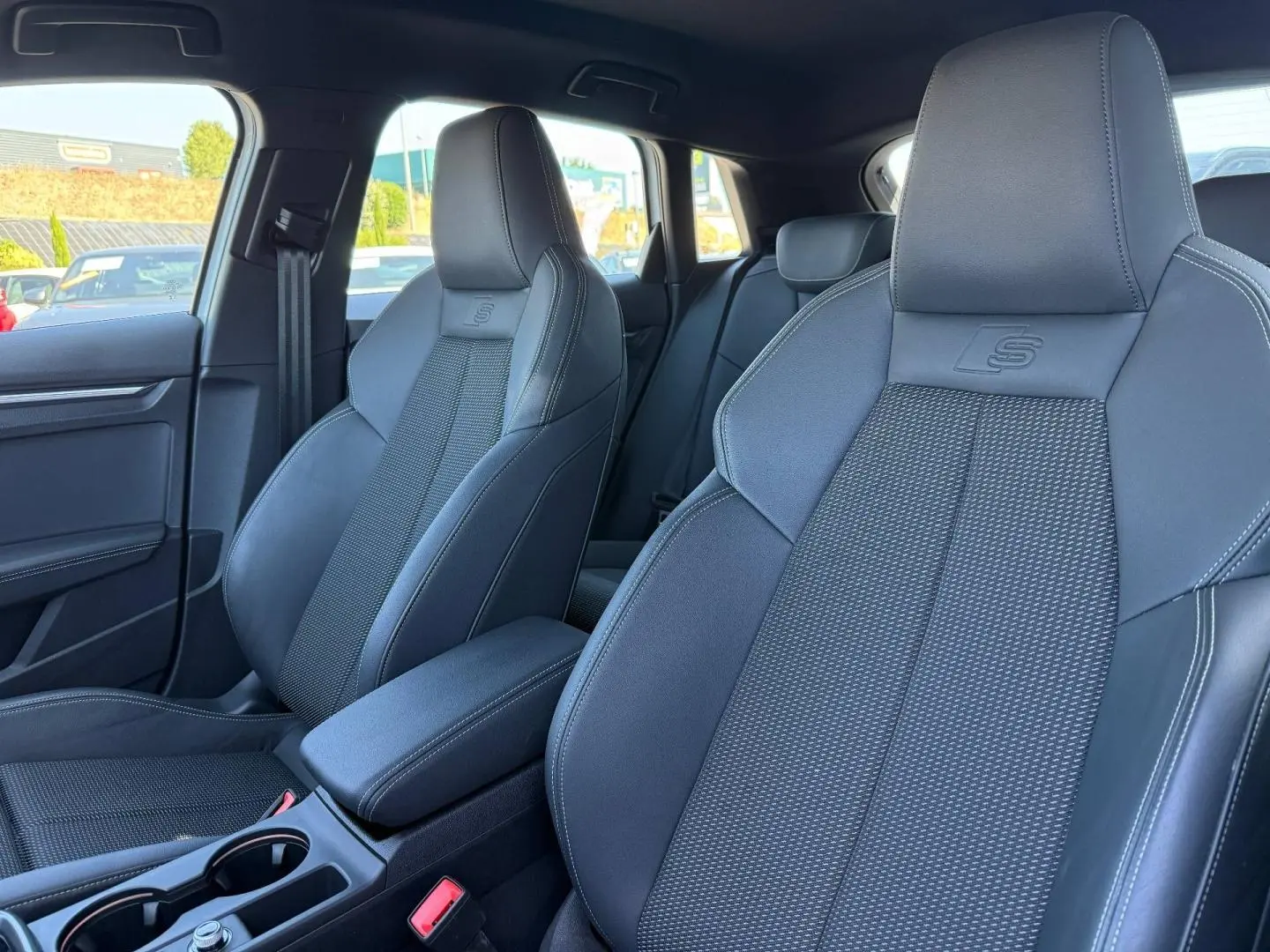 Intérieur de l'Audi A3 Sportback 2025, vue rapprochée des sièges avant sport noirs avec logo S embossé.