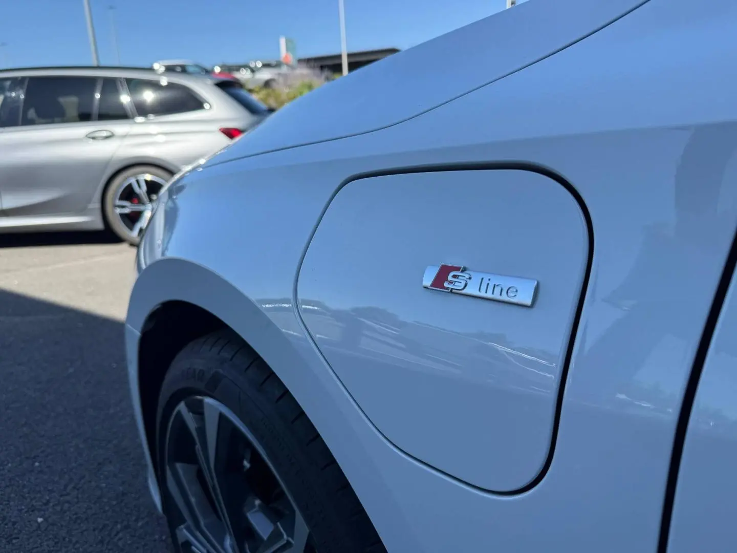 Gros plan sur l'aile avant gauche blanche Glacier métallisé d'une Audi A3 Sportback 2025 avec logo S line.