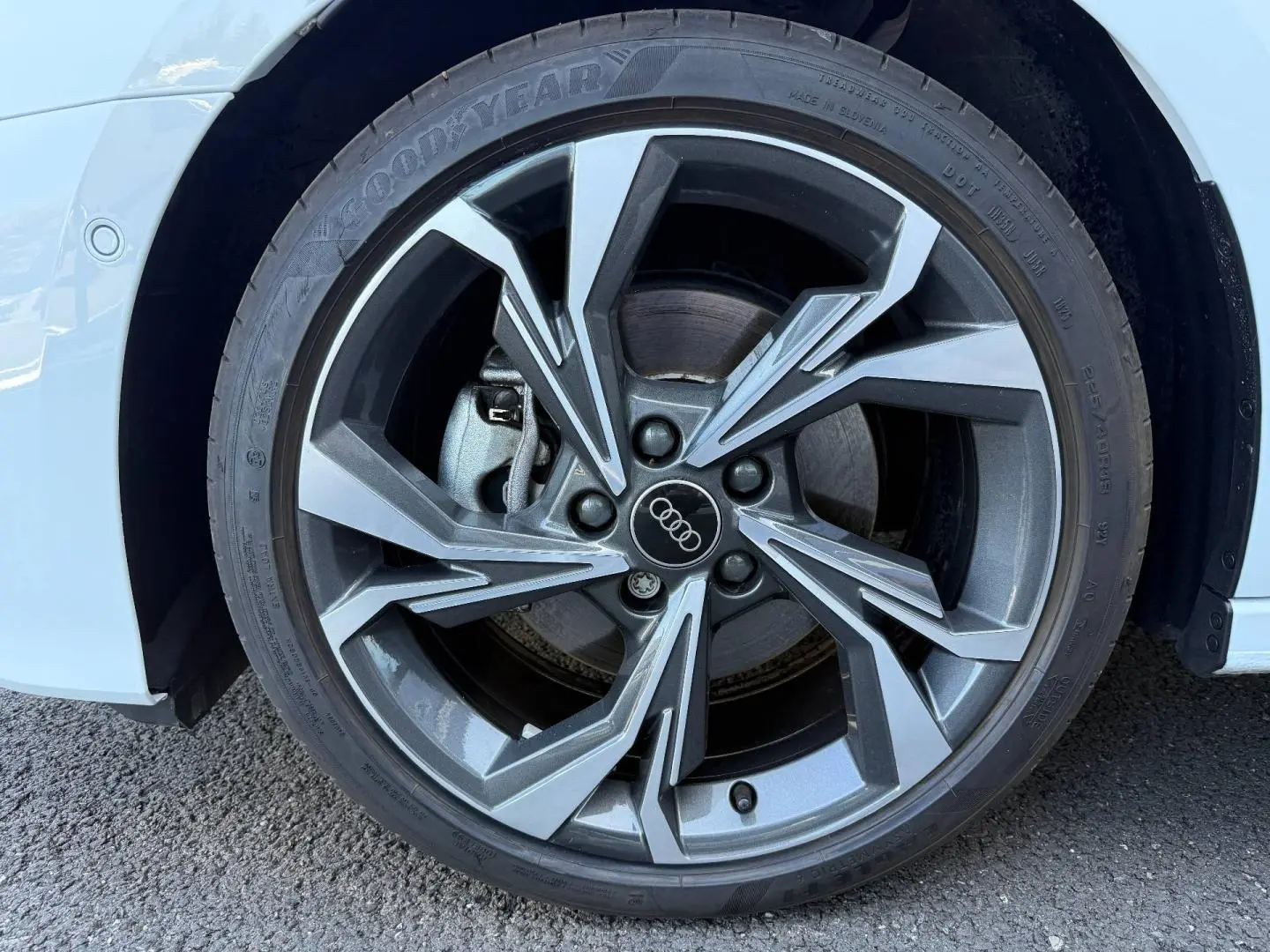 Gros plan sur la jante alu grise à design géométrique de l'Audi A3 Sportback blanc Glacier métallisé, côté avant droit.