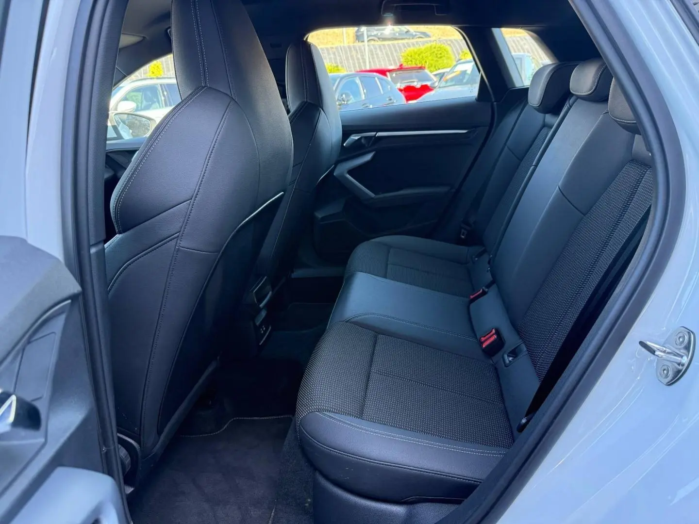 Vue intérieure côté droit sur la banquette arrière noire en tissu et simili de l'Audi A3 Sportback Blanc Glacier 2025.