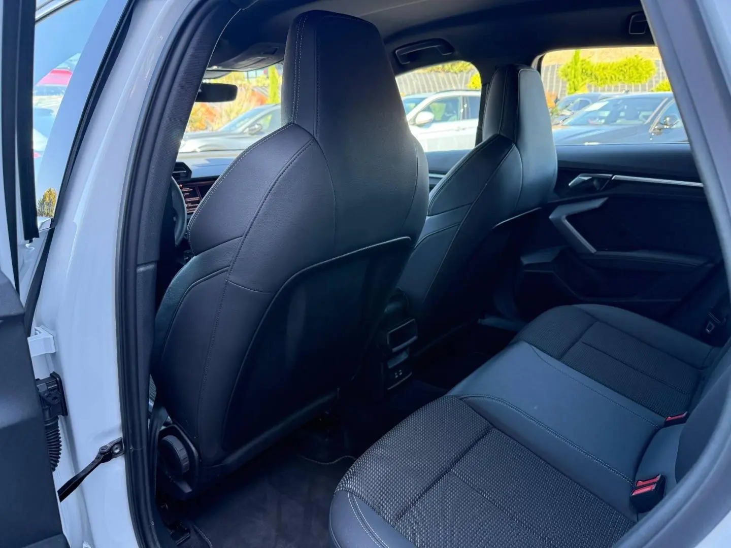 Vue intérieure arrière côté gauche de l’Audi A3 Sportback 2025 blanc Glacier, sièges sport noirs en tissu et simili.