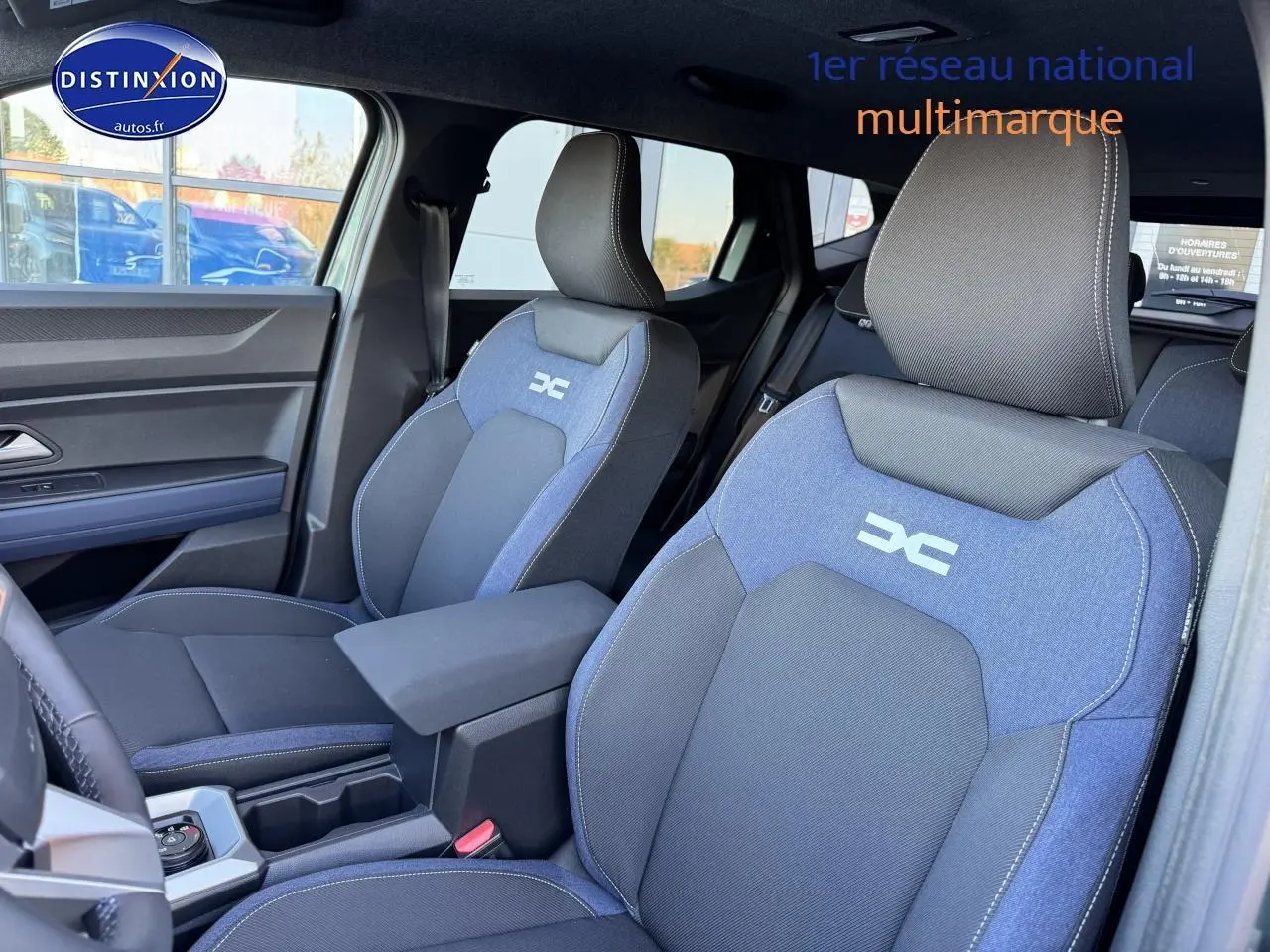 Vue intérieure côté gauche montrant les sièges avant bleu et noir avec logo Dacia sur un Dacia Duster 2025.
