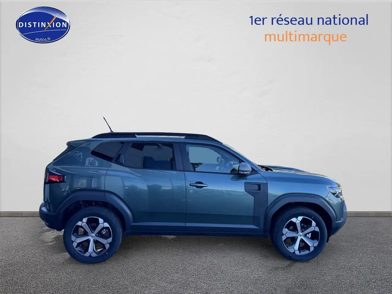 Profil droit du Dacia Duster 2025 vert cèdre avec jantes alu et barres de toit visibles.