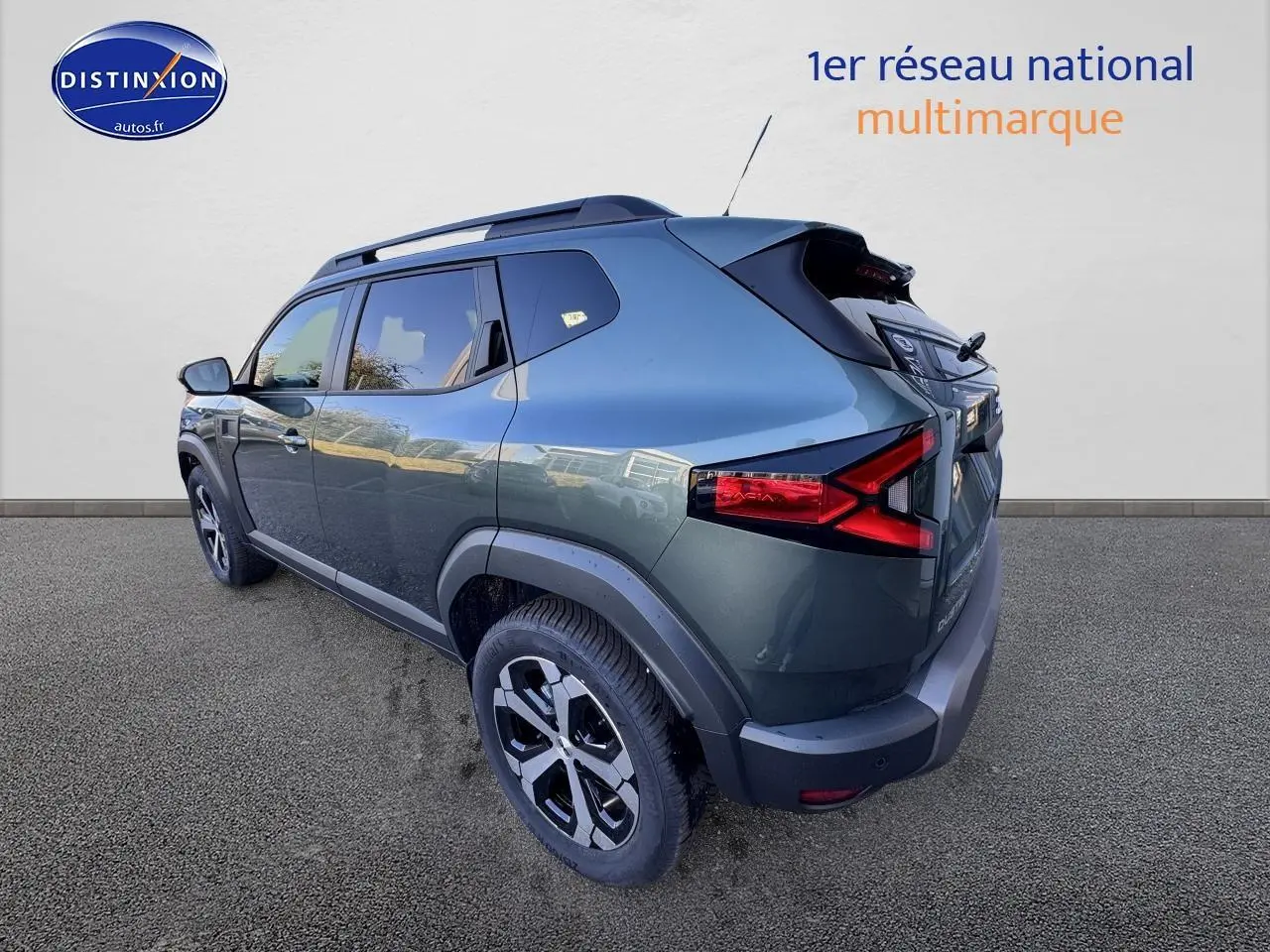 Vue 3/4 arrière droite du Dacia Duster 2025 vert cèdre avec barres de toit et jantes alu noires.