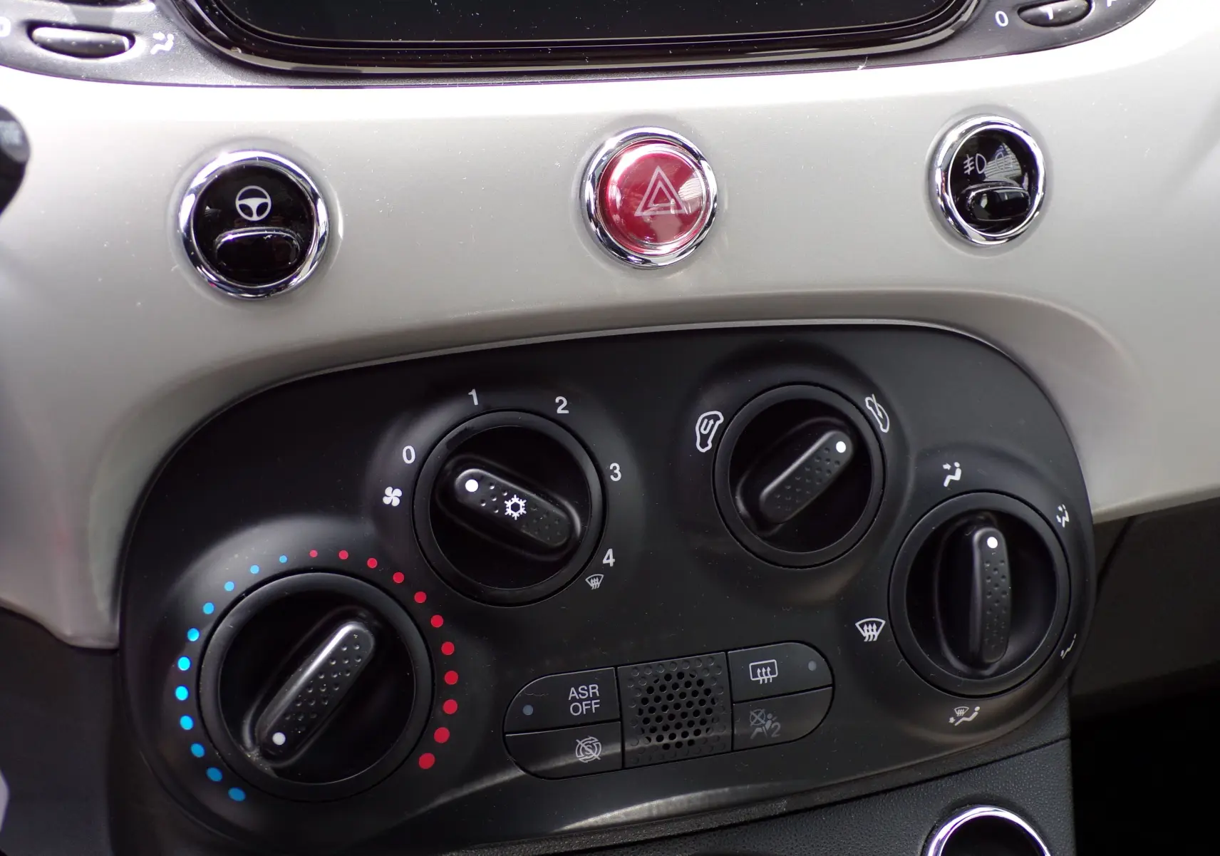 Détail du tableau de bord de la Fiat 500 blanc 2019 montrant les commandes de climatisation et les boutons de sécurité.