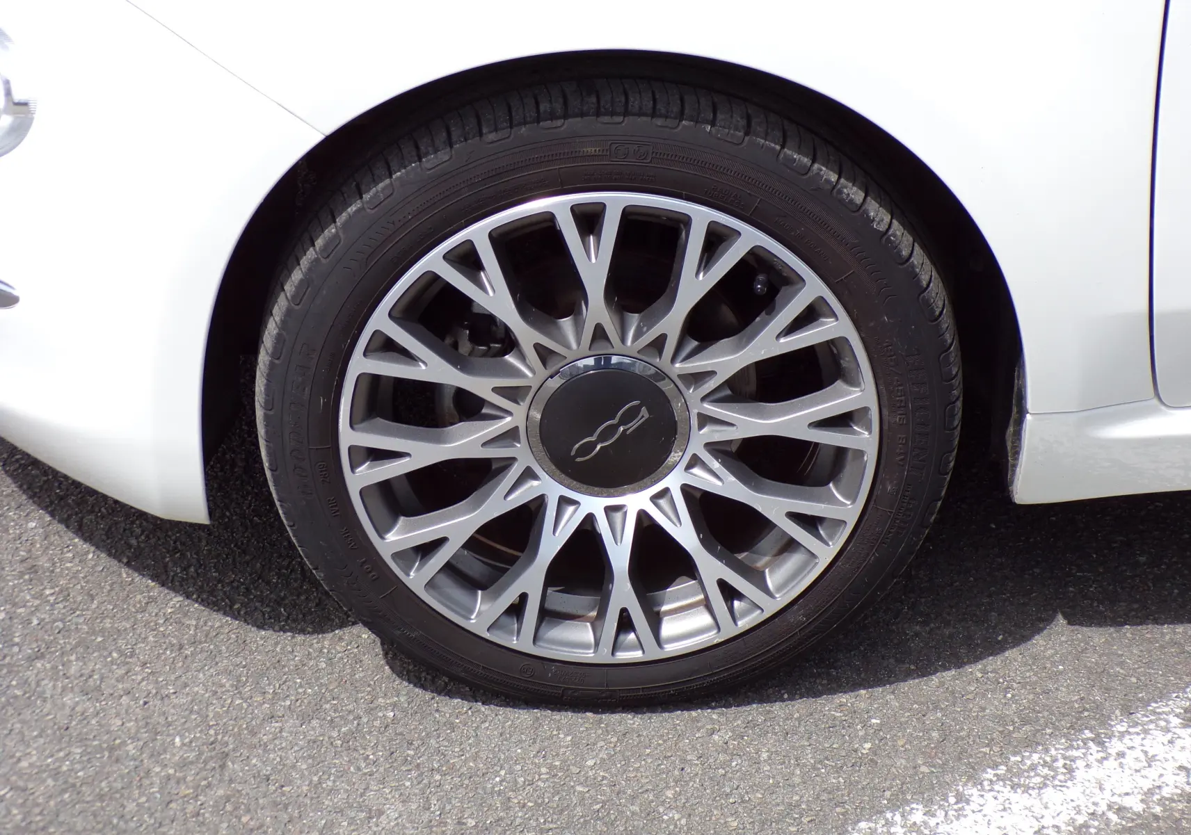 Gros plan sur la roue avant droite de la Fiat 500 blanche de 2019 avec jante alliage multibranches argentée.