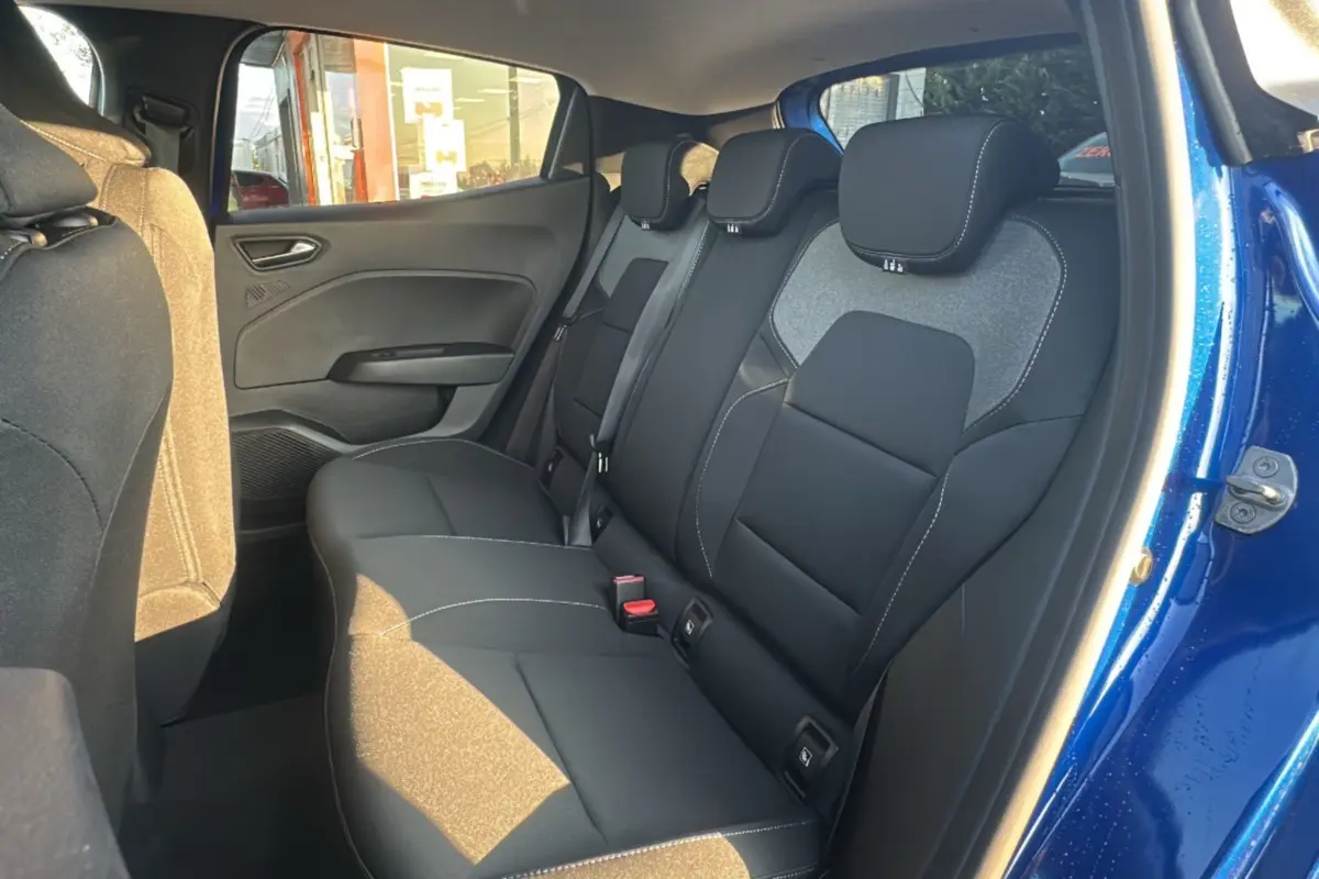 Vue intérieure arrière droite de la Renault Clio 2025 bleu iron, montrant les sièges arrière en tissu noir avec surpiqûres blanches.