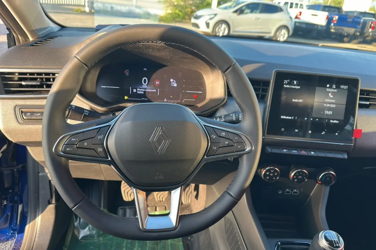 Vue intérieure centrée sur le volant de la Renault Clio DCI 100 Evolution Camera 2025, avec tableau de bord digital et écran tactile.