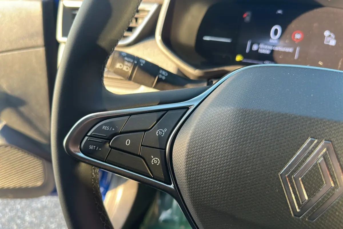 Gros plan sur le volant de la Renault Clio DCI 100 Evolution Camera 2025 bleu iron, avec commandes de régulateur de vitesse.