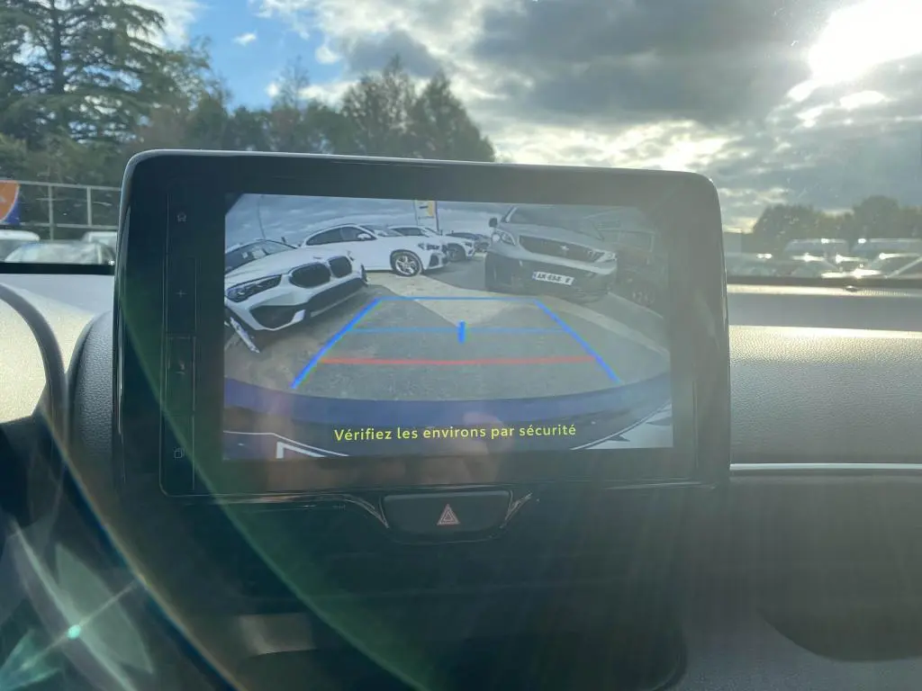 Écran tactile intérieur montrant la caméra de recul d'une Toyota Yaris hybride 2025, avec vue arrière sur un parking.
