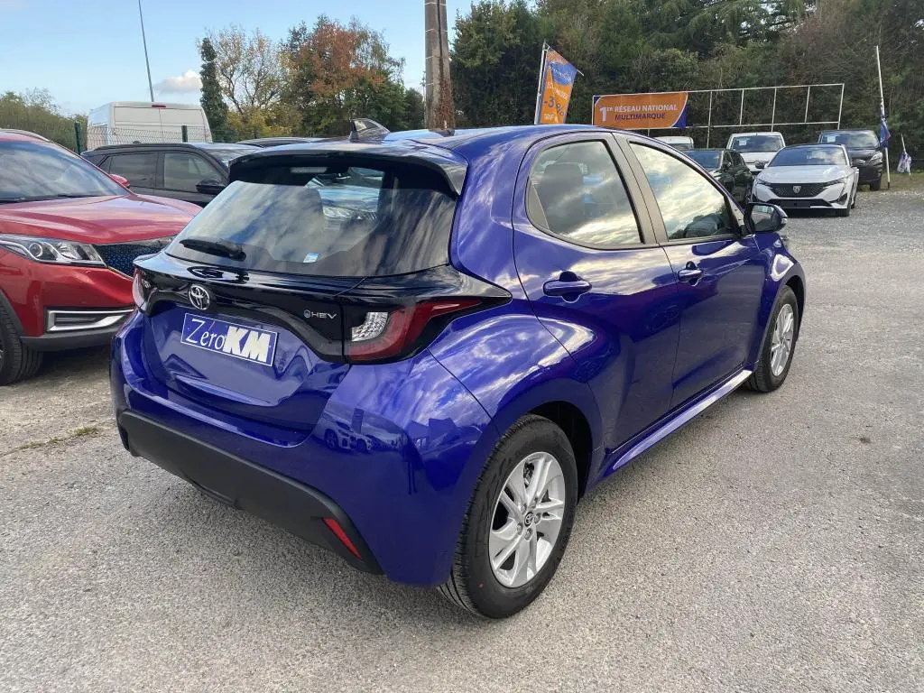 Toyota Yaris hybride 2025 bleu Genièvre vue 3/4 arrière droit avec jantes alliage 15 pouces et toit noir brillant.