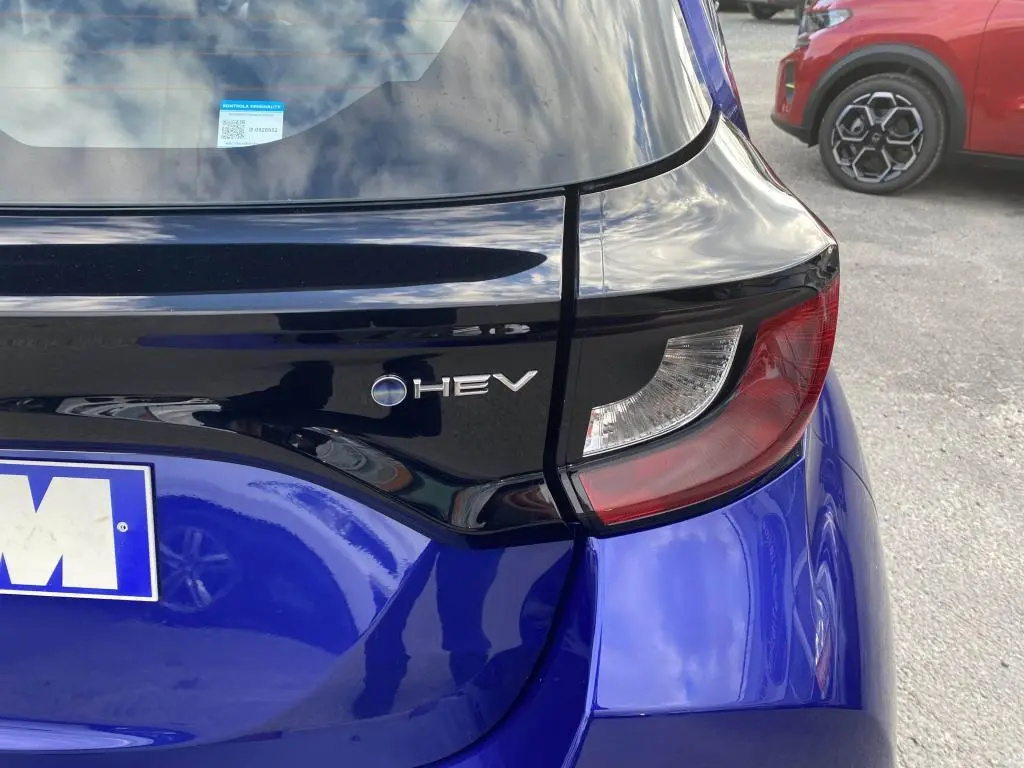 Gros plan sur le feu arrière droit et le logo HEV d'une Toyota Yaris hybride 2025 en bleu Genièvre.
