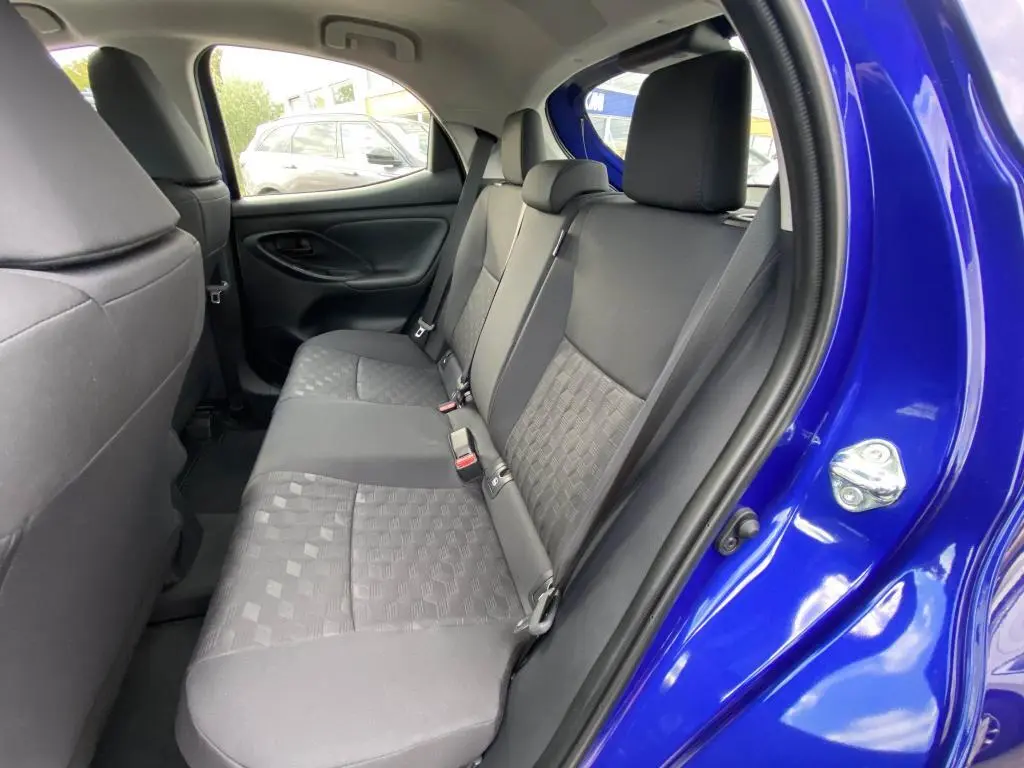 Vue intérieure côté droit sur la banquette arrière noire d'une Toyota Yaris 2025 bleu Genièvre avec porte ouverte.