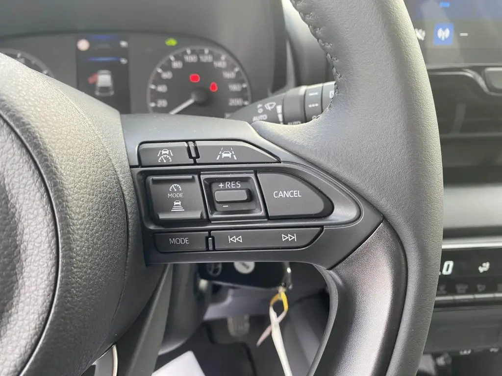 Gros plan sur les commandes au volant à droite de la Toyota Yaris 2025, avec tableau de bord et écran tactile en arrière-plan.
