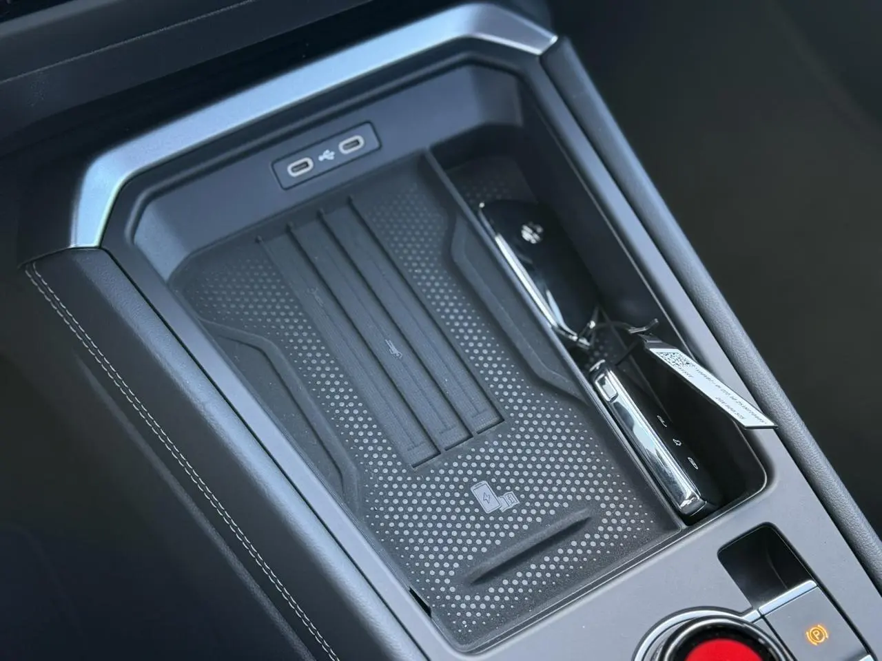 Gros plan sur la console centrale noire du Volkswagen T-Roc 2026 avec zone de recharge sans fil et ports USB-C.