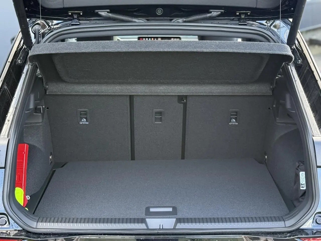 Coffre ouvert d'un Volkswagen T-Roc noir ébène, vue arrière montrant l'espace de chargement vide et la trappe supérieure.