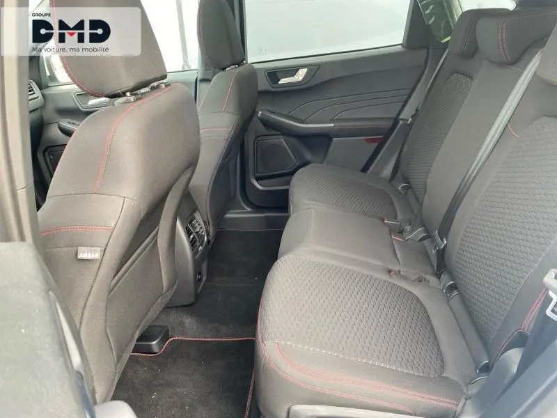 Vue intérieure arrière côté droit du Ford Kuga 2026, sièges tissu noir avec surpiqûres rouges et ceintures grises.