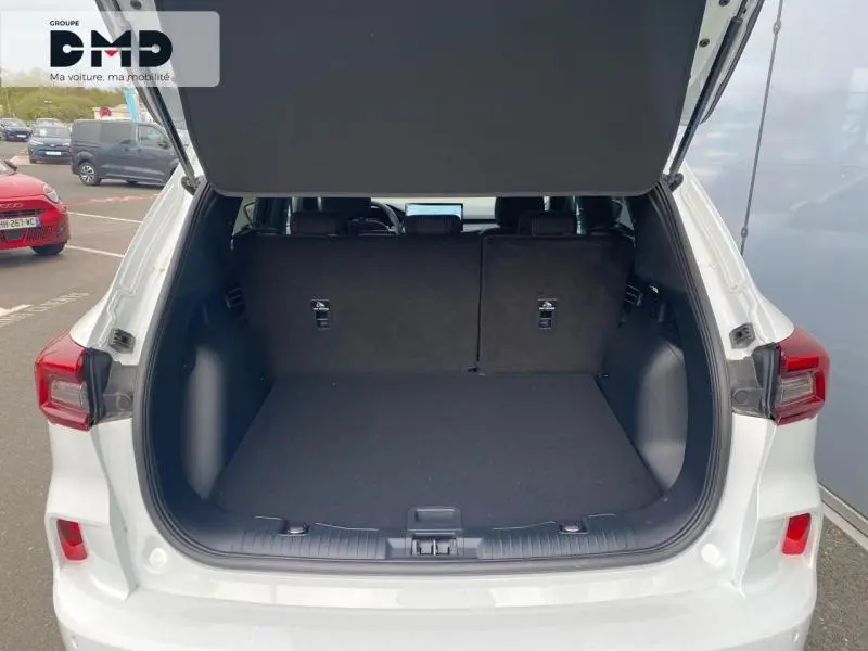 Coffre ouvert vu de l'arrière d'un Ford Kuga blanc Glacier, montrant un espace de chargement spacieux et propre.