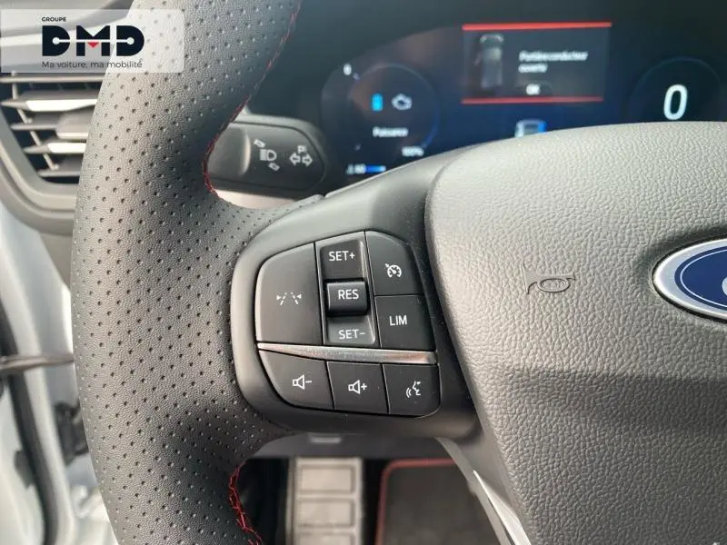 Gros plan sur le volant perforé noir avec surpiqûres rouges du Ford Kuga blanc, boutons multifonctions visibles.