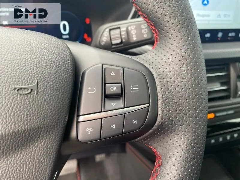 Gros plan sur le volant perforé avec surpiqûres rouges et commandes multifonctions du Ford Kuga blanc Glacier 2026.
