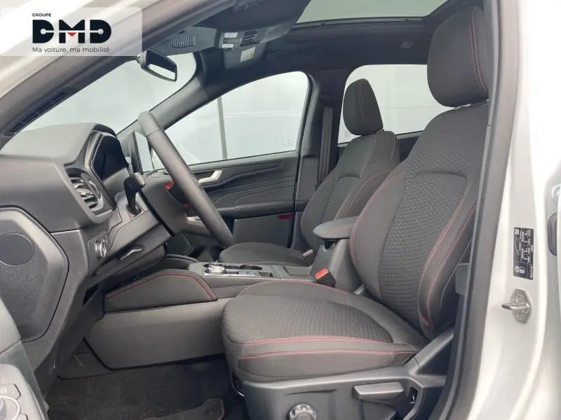 Intérieur avant droit du Ford Kuga blanc Glacier 2026, sièges tissu noir avec surpiqûres rouges et toit ouvrant panoramique.