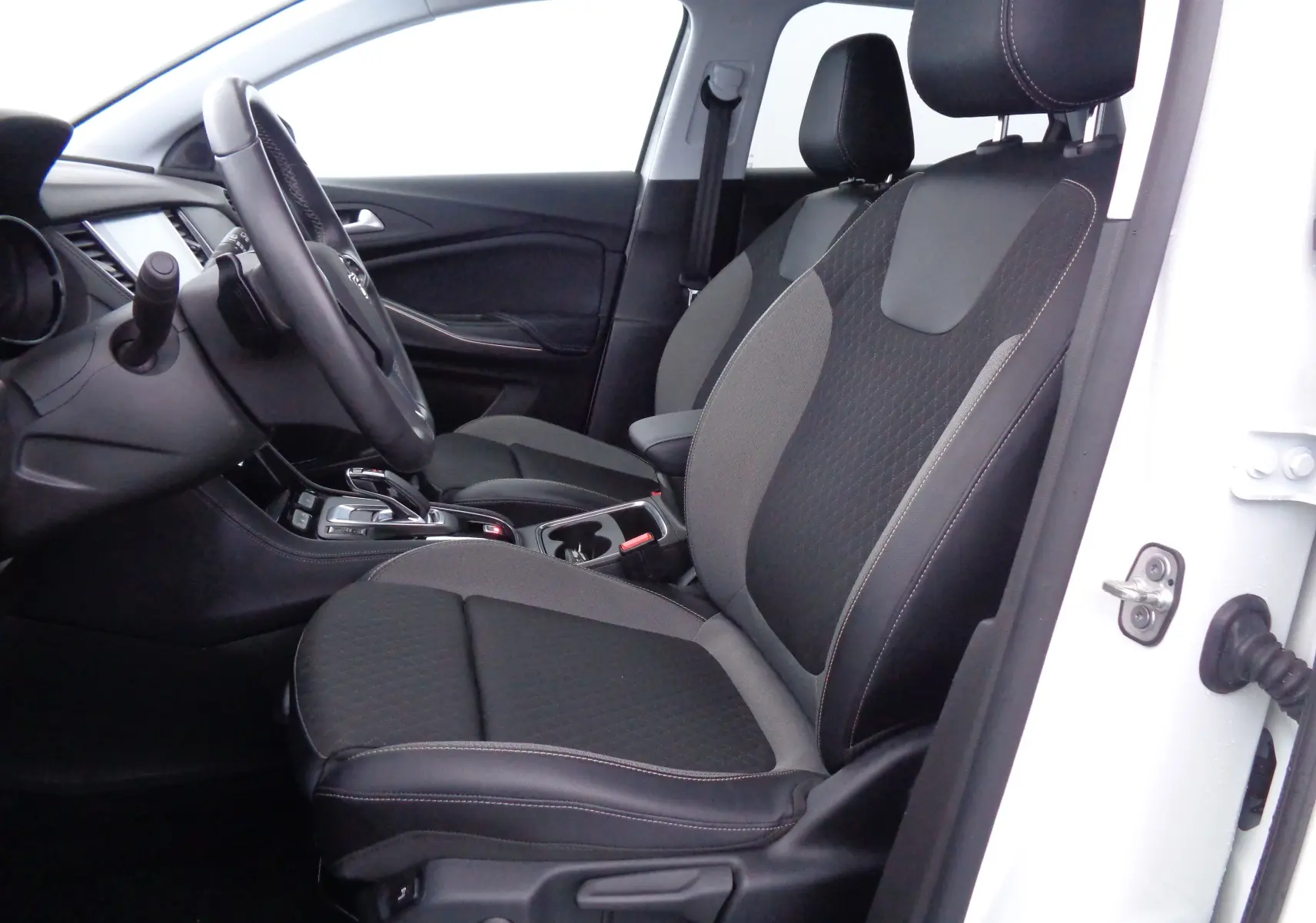 Intérieur côté conducteur de l'Opel Grandland X blanc perle, sièges bi-matière noirs et gris avec coutures apparentes.