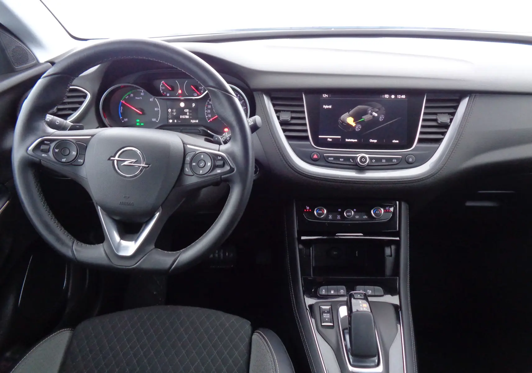Vue intérieure avant de l'Opel Grandland X hybride, tableau de bord noir avec écran tactile et volant multifonction.