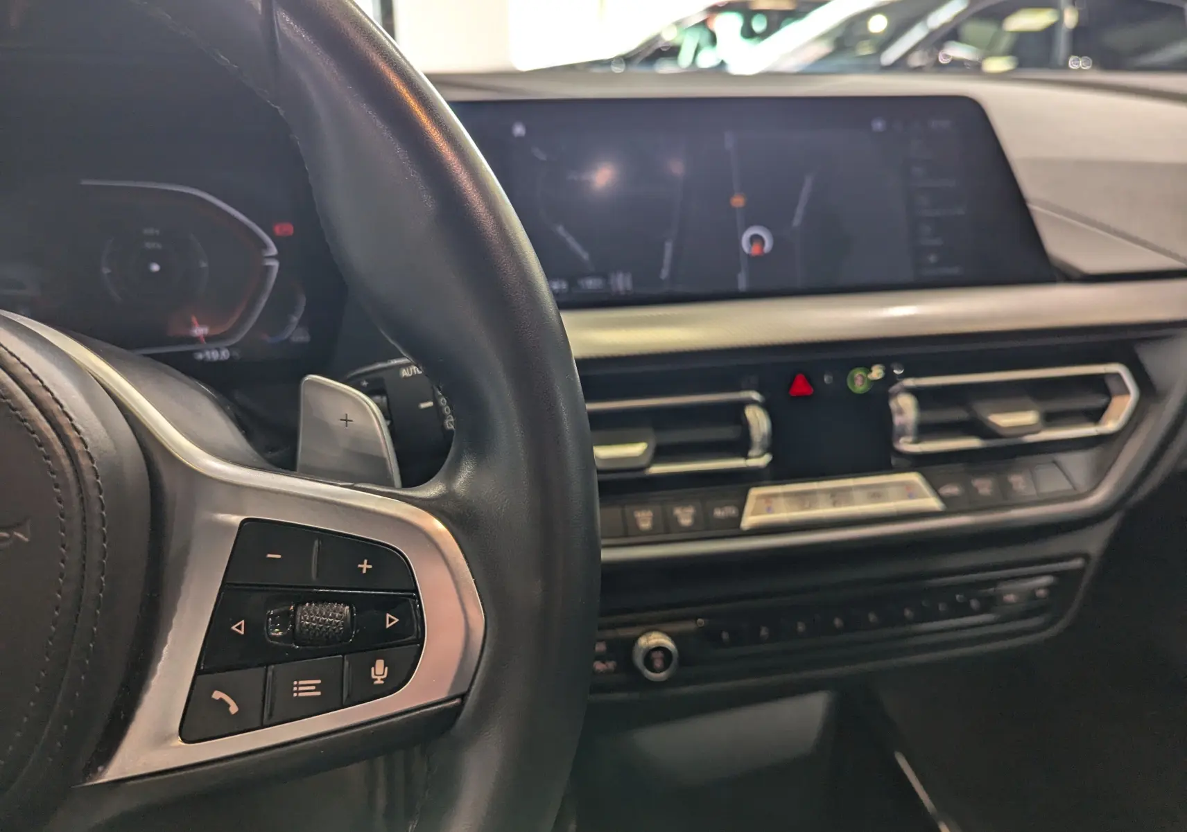 Vue rapprochée de l'intérieur côté conducteur de la BMW Série 1 F40, volant cuir noir et écran tactile central.