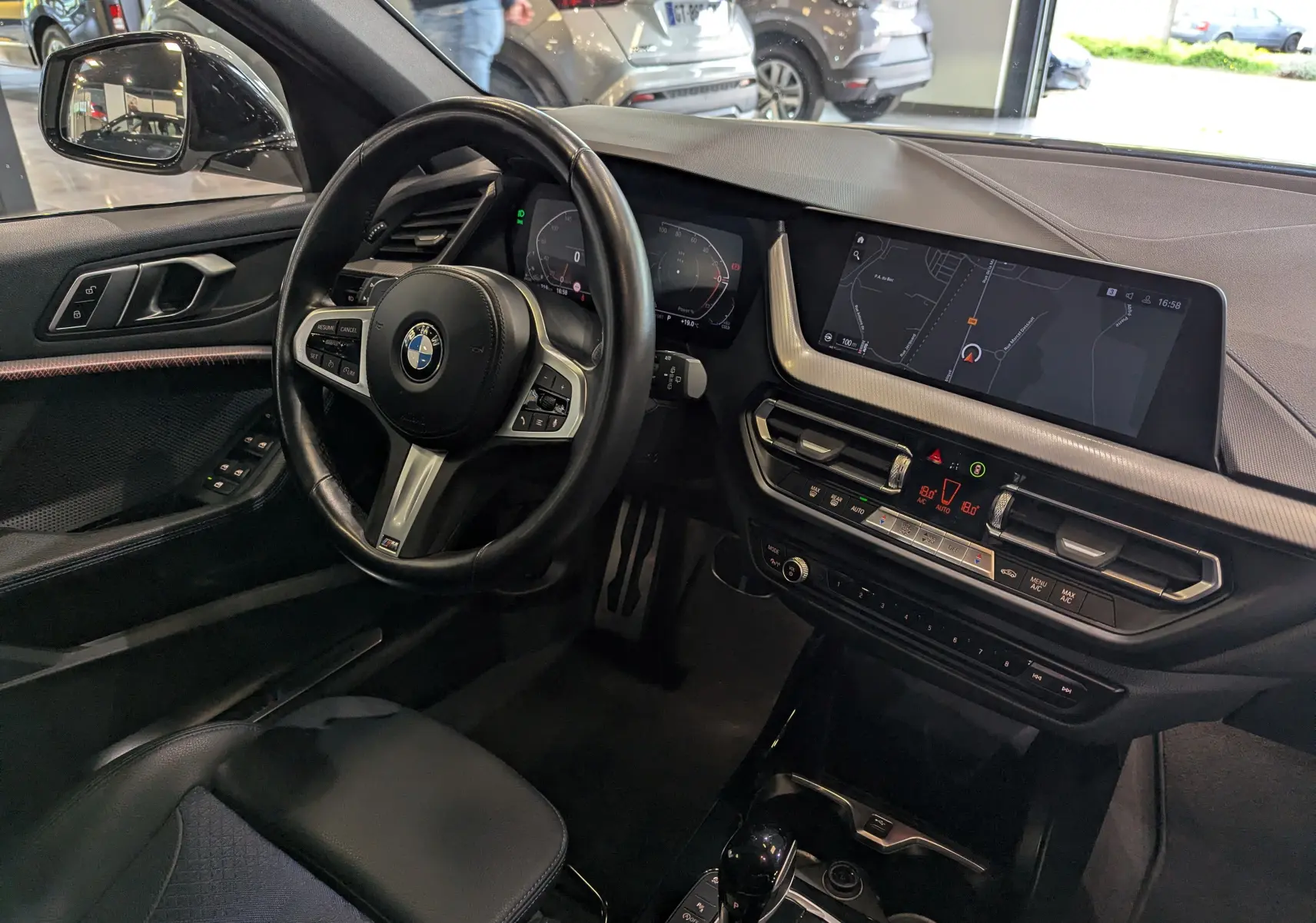 Vue intérieure côté conducteur de la BMW Série 1 F40 18d M Sport 2023, avec tableau de bord numérique et écran tactile GPS.